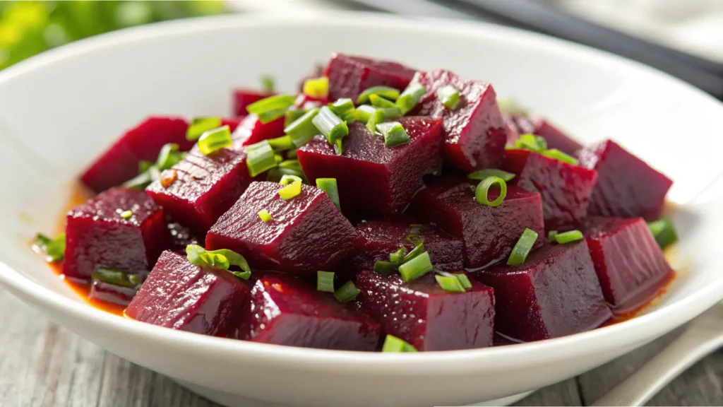 Close-up of a Russian beet salad with vibrant beet cubes garnished with freshly chopped green onions, served in a white bowl.